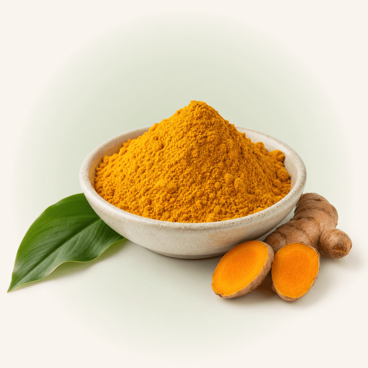 Golden turmeric root powder displayed with fresh turmeric root and green leaves